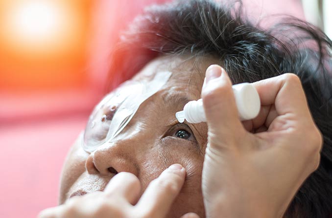 Một y tá bôi thuốc nhỏ mắt chữa bệnh đục thủy tinh thể vào mắt cho một bệnh nhân lớn tuổi. Một y tá bôi thuốc nhỏ mắt chữa bệnh đục thủy tinh thể vào mắt cho một bệnh nhân lớn tuổi.